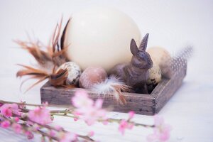 Still-life arrangement of various eggs, rabbit ornament and pink-flowering branches