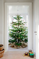 View of large decorated Christmas tree seen through open door