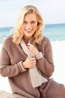 Blonde Frau in brauner Strickjacke am Strand