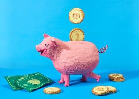 Papier mâché piggy bank and money to represent saving