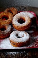 Doughnuts being sprinkled with icing sugar