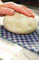 Dough being rolled over a wet cloth to moisten it