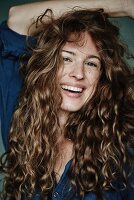 A brunette woman with curly hair, wearing a blue blouse