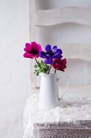 Anemones in jug on lace doily on chair