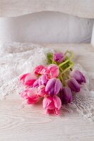Pink and purple tulips on lace doily on white chair