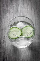 A glass of water with cucumber slices and ice cubes