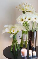 Arrangement of white flowers and lit candles on black table