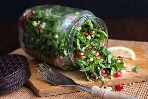 Millet taboule in a glass jar with pomegranate seeds, parsley and mint