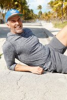 A man in sportswear lying on a beach promenade