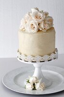 A layered vanilla cake with roses on a cake stand for a special occasion