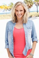 A blonde woman wearing a pink top and denim shirt