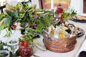 Verschiedene Getränke in Vintage Wanne, Flusskrebs und Blumendeko auf gedecktem Tisch