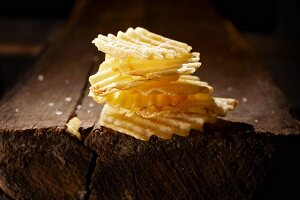 A stack of crinkle cut potato crisps on a wooden table