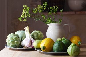 A still life with round courgettes, garlic and artichokes