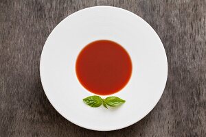 Gazpacho and tomato soup garnished with a basil leaf