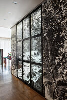 Partition wall covered with black-and-white photo mural and window frames in open-plan interior