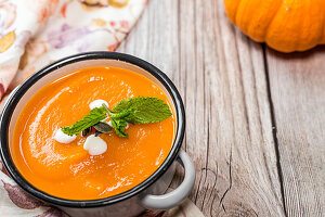 Homemade creamy pumpkin soup with mint in an enamel pot
