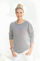 A young blonde woman with a bun wearing a grey jumper