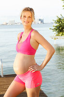 Schwangere Frau in rosa Bustier und Shorty am Steg