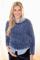 A young blonde woman wearing a denim shirt and a blue jumper