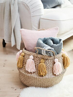 A basket for cushions and blankets decorated with DIY tassels