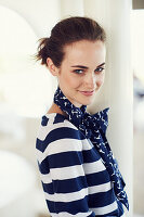 A young brunette woman wearing a blue-and-white striped jumper and a scarf