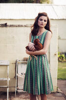 Junge Frau im Sommerkleid mit Huhn auf dem Arm