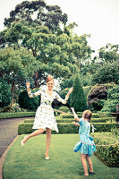 A mother and daughter playing with hula hoops in a garden
