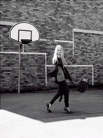 Junge Frau in dunklem, sportlichem Outfit auf Basketballplatz (s-w-Aufnahme)