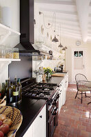 Gas cooker and terracotta floor tiles in narrow country-house kitchen