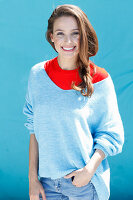 A brunette woman wearing a blue jumper over a red top