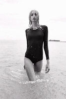 A blonde woman in the sea wearing a black bathing suit (black-and-white shot)