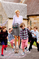 A blonde woman playing with children outside a church