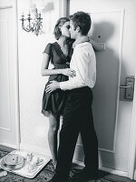 A young couple kissing outside a hotel room (black-and-white shot)
