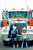 A blonde woman and a child dressed as a robot standing in front of a truck