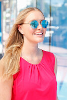 Blonde Frau in pinkfarbenem Top mit Sonnenbrille