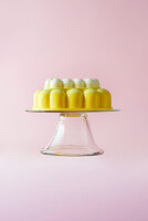 A Lemon Merringue Jelly on a cake stand on a pink background