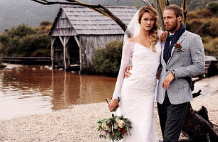 A bride and groom with a bouquet by a lake