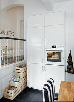 Weißer Schrank mit integriertem Backofen neben Treppengeländer in der Küche