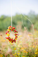 Wreath of rose hips and yellow flowers in garden