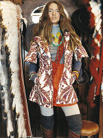 A young woman wearing a printed coat standing next to feather accessories