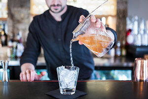 A bartender pouring a cocktail