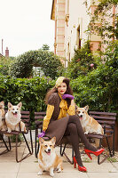 Dunkelhaarige Frau in braunem Kleid mit Hunden auf Bank sitzend
