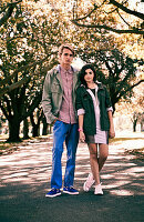 A young couple standing under trees