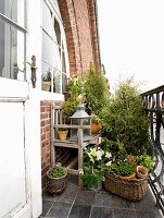 Holzbank, Laterne und Topfpflanzen auf Balkon
