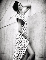 A young woman wearing a black turban headband and an elegant white dress with black polka dots (black-and-white shot)