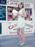 Young woman wearing pale blue dress and matching ballet flats holding candyfloss