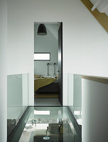 Glass walkway with glass balustrade leading to bedroom in architect-designed house