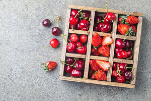 Mix of fresh berries in vintage wooden box on rustic background