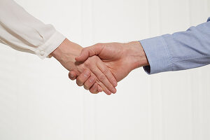 A man's hand holding a stretched out woman's hand (body language: distanced handshake)